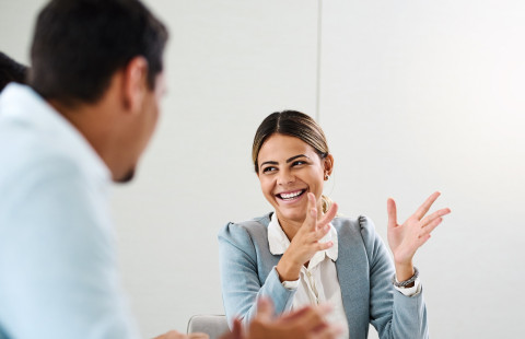 Kaksi henkilöä keskustelee pöydän ääressä.