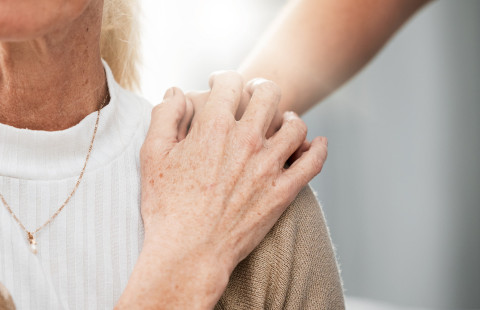 Kädet iäkkään ihmisen olkapäällä.