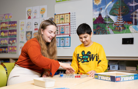 logopedian opiskelija pelaamassa lautapeliä lapsen kanssa