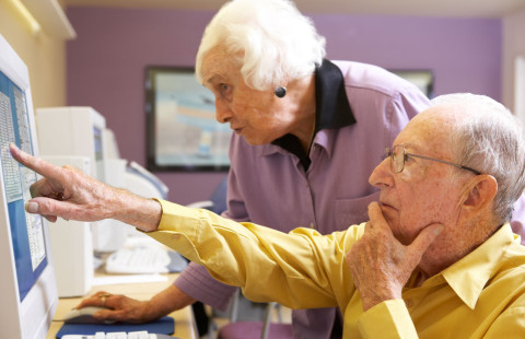 Iäkäs mies ja nainen tietokoneen ruudun ääressä.