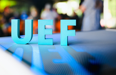 UEF kirjaimet tason päällä, edustalla kirjaimista muodostuva varjo