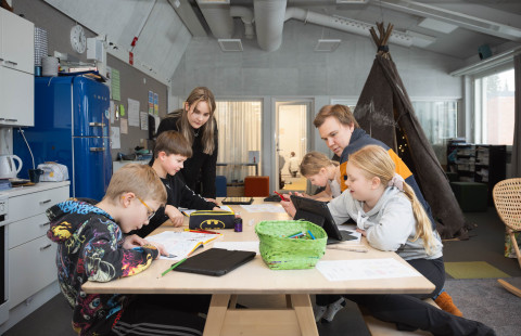 Opettajat tekemässä koululaisten kanssa tehtäviä.