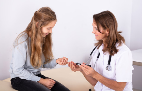 Doctor measuring child&#039;s blood sugar.