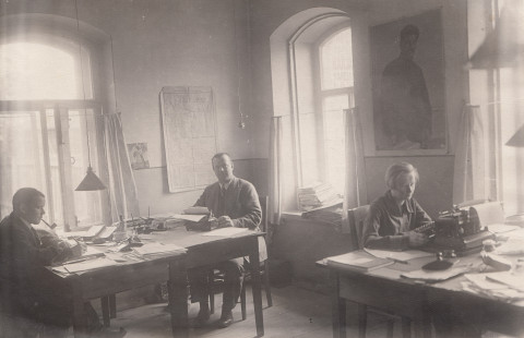 Ihmisiä toimistopöytien ääressä.