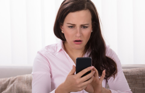 Shocked woman looking at mobile phone.