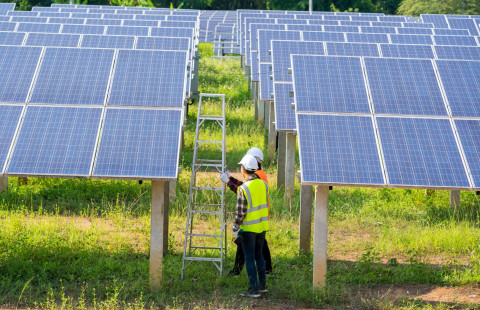 Kypäräpäisiä ihmisiä aurinkovoimalassa.