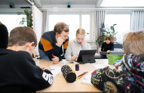 Opettajat tekemässä koululaisten kanssa tehtäviä.