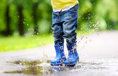 Lapsi hyppää lätäkköön kumikenjät jalassa.