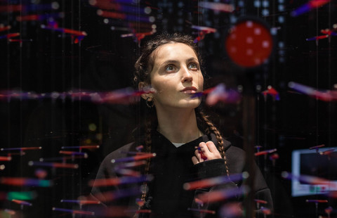 Henkilö punertavien valoheijastusten keskellä pimeässä