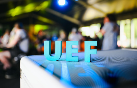 UEF-kirjaimet ja yleisöä taustalla.