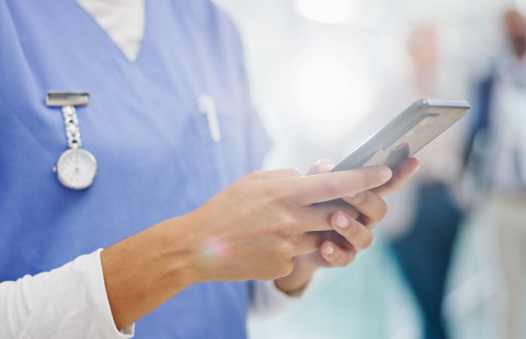 Sairaanhoitaja selaa matkapuhelinta.