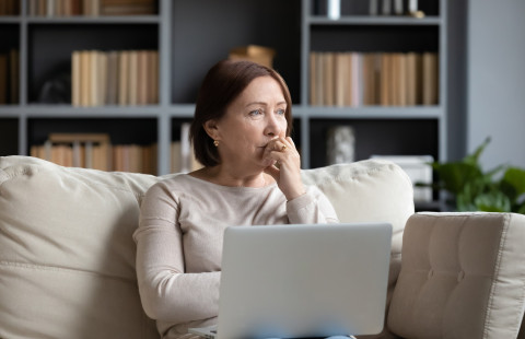 Keski-ikäinen nainen etätöissä tietokoneella.