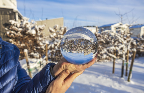 Henkilö pitää käsissään lasipalloa talvimaisemassa