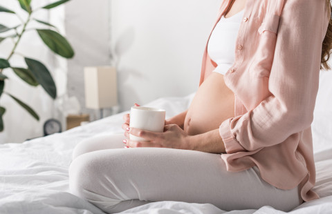 Odottava äiti kahvikuppi kädessä.