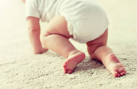 Vauva konttaa matolla.