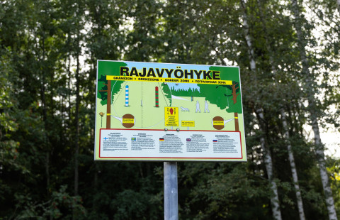 Opastaulu rajavyöhykkeestä taustalla koivumetsä.