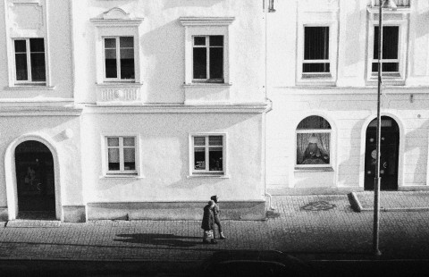 Black and white photo two persons walking in front of a builing
