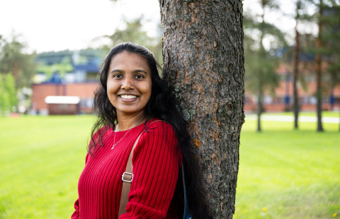 Student leaning on a tree and smiling
