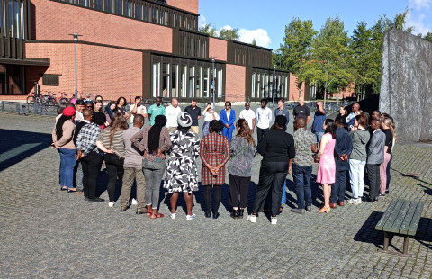 People gathered in a circle in the square in front of a building.