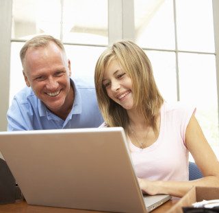 Isä ja tytär tietokoneen äärellä. 