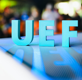 UEF kirjaimet tason päällä, edustalla kirjaimista muodostuva varjo