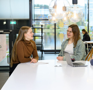 Opiskelijoita Snellmanian ala-aulassa pöydän ääressä