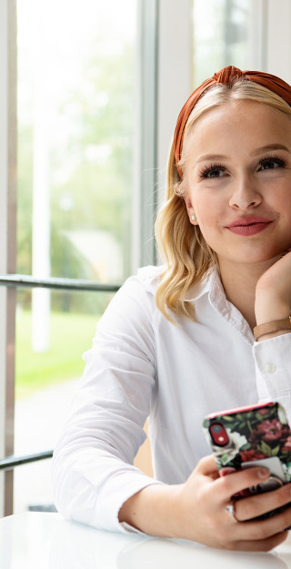 UEF-lähettiläs istuu kännykkä kädessä