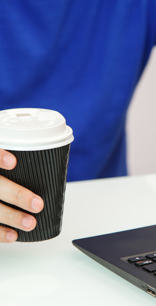 Hands holding coffee and laptop