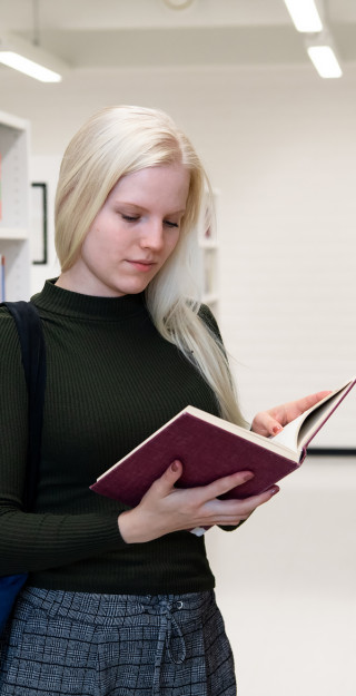 Naispuolinen opiskelija lukee kirjaa UEFin kirjastossa.