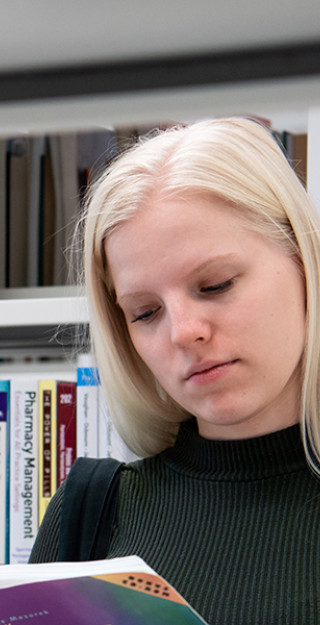 UEF-lähettiläs Mirka Nieminen kirjastossa selaamassa kirjaa